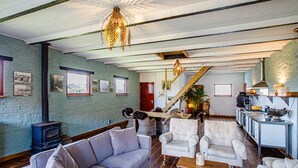 Uma sala de estar espaçosa com lareira, assentos confortáveis e cozinha equipada com eletrodomésticos modernos.