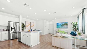 Une cuisine moderne avec des meubles blancs, des appareils en acier inoxydable et un îlot central.