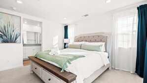Une chambre moderne avec un grand lit, une table de chevet, un miroir et une vue sur la salle de bain.