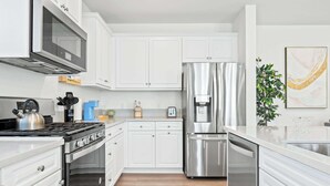 Une cuisine moderne avec des armoires blanches, des appareils en acier inoxydable et un plancher en bois.