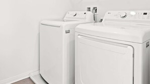 Une buanderie équipée de deux machines à laver à chargement frontal, de couleur blanche, et d’un étendoir.