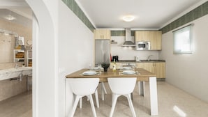 Une cuisine moderne avec une table à manger en bois, des chaises blanches et un four à micro-ondes encastré.