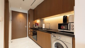 A modern kitchen with wooden cabinets, a built-in dishwasher, a microwave, and a coffee maker. - Luxury Studio with Pool - Azizi Vista (Dubai)