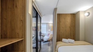 A modern hotel room with a wooden accent wall, a glass door leading to a sitting area, and a neatly made bed. - NOK Stylish 1BR With Cozy Terrace (Bogotá)