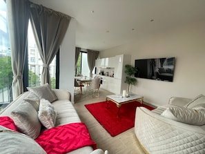 Ein modernes Wohnzimmer mit einer Couch, einem roten Teppich und einem Essbereich mit Tisch und Stühlen.