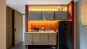 Una cocina compacta con refrigerador integrado, un lavamanos y gabinetes de madera.