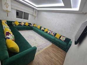 Een moderne woonkamer met een groene bank, een gekleurd vloerkleed en een houten vloer.