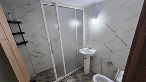 Een badkamer met een douche, toilet en wastafel.