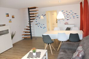 A modern living room with a dining area, a staircase, and a bed.