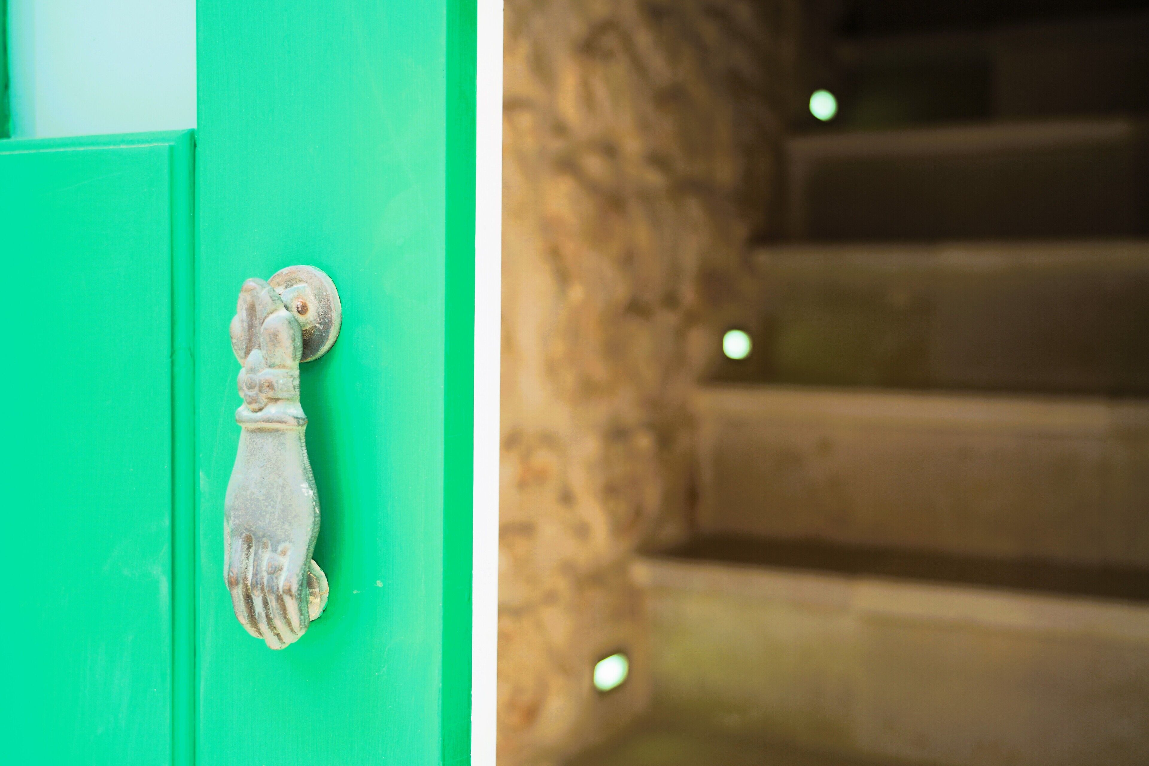 A green door with a hand-shaped door knocker.