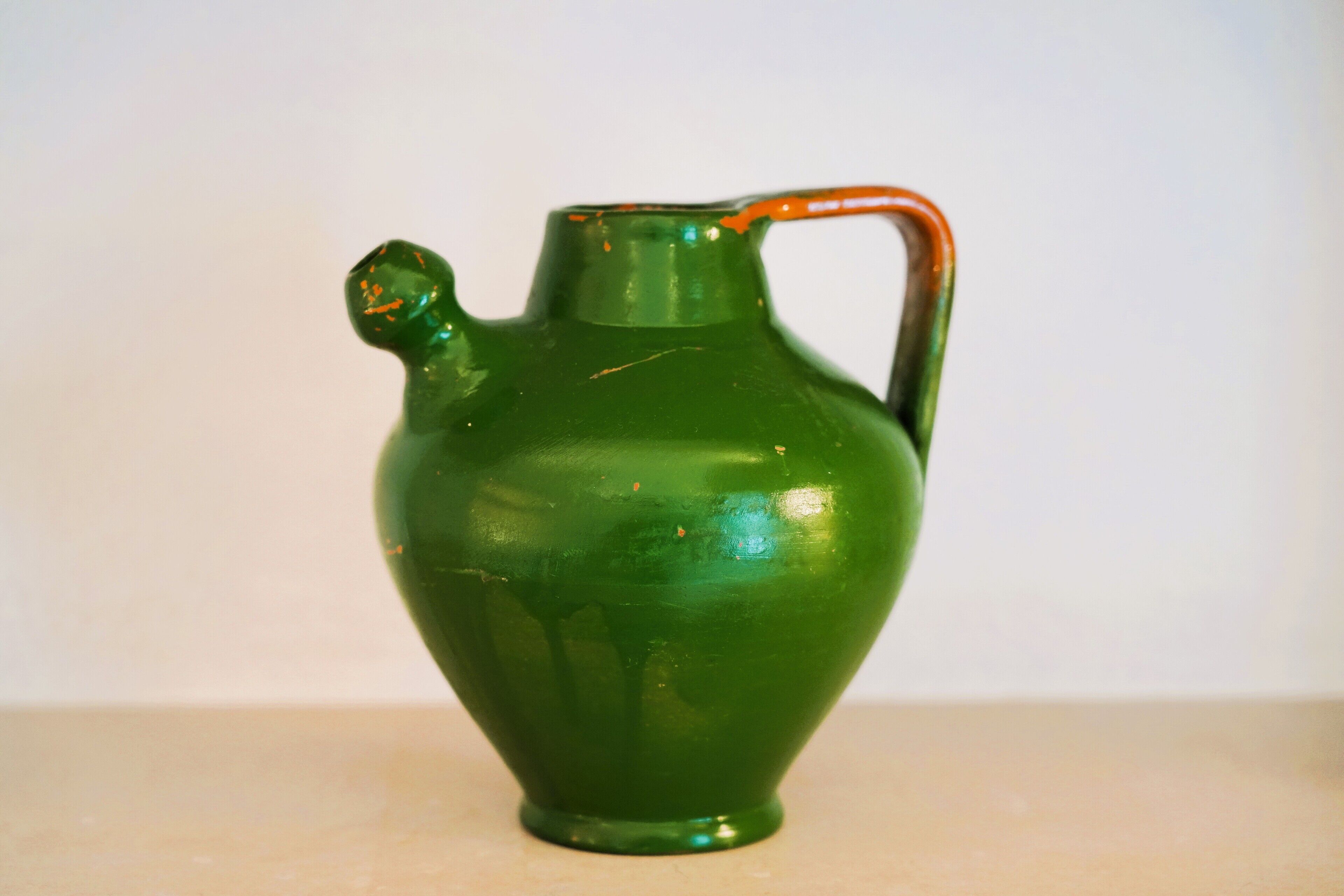 Una jarra verde de cerámica con asa.