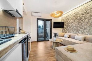 Una cocina moderna con lavavajillas, un comedor con mesa redonda y una sala de estar con sofá y pared de piedra.