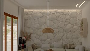 Un salon moderne avec un mur en pierre, un canapé, une table basse et un luminaire suspendu.