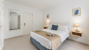 Une chambre d’hôtel avec un grand lit, deux tables de chevet avec des lampes, un miroir et un tableau encadré au mur.