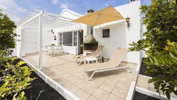 Une terrasse avec un barbecue, des chaises longues et une pergola.