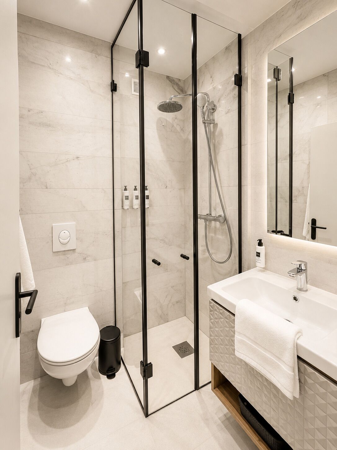 A modern bathroom with a glass-enclosed shower, a white toilet, and a sink with a mirror.