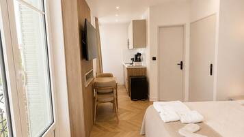 Una habitación de hotel con cama, escritorio, silla, televisor y ventilador de techo.