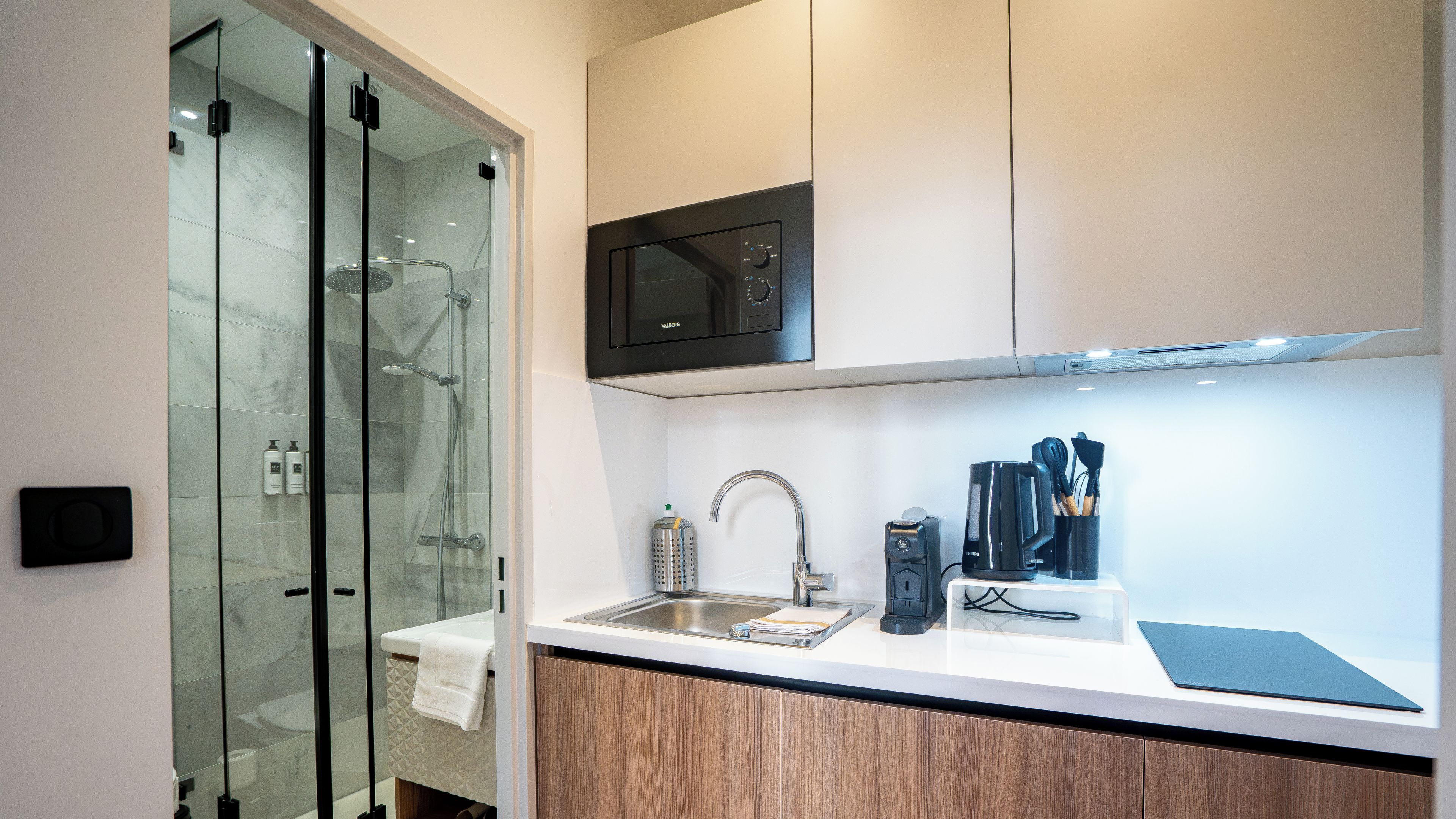 Una cocina moderna con microondas integrado, un lavabo y una cafetera.