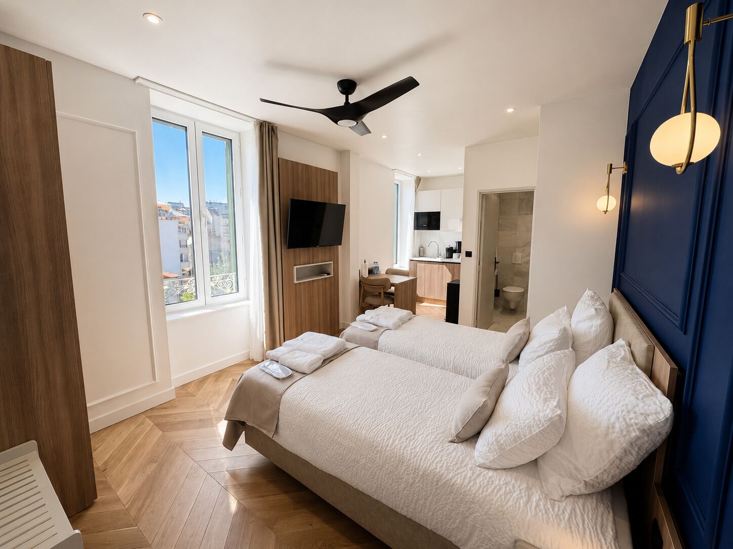 Ein modernes Hotelzimmer mit einem großen Bett, einem Schreibtisch, einem Flachbildfernseher und Blick auf die Stadt.