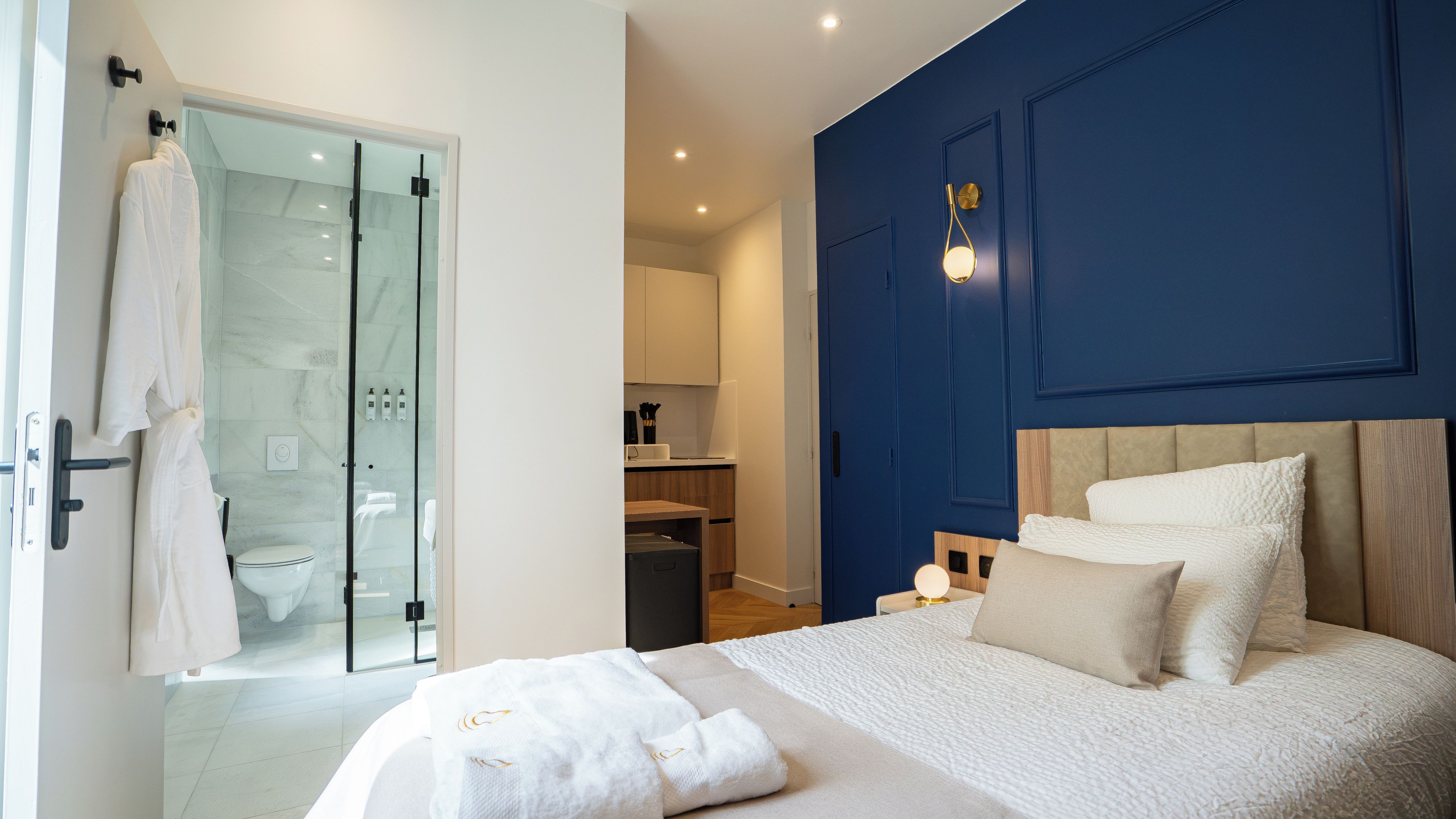 Una camera da letto moderna con un letto grande, cabina doccia in vetro e una parete decorata in blu.