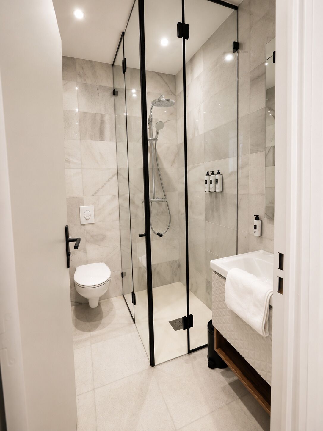 Une salle de bain moderne avec une douche à parois de verre, des toilettes et un lavabo avec une serviette.