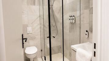 Une salle de bain moderne avec une douche à parois de verre, des toilettes et un lavabo avec une serviette.