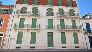 A multi-story building with balconies, a central entrance, and a clear sky.