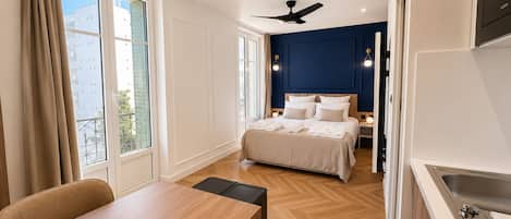 A hotel room with a bed, bedside tables, a desk, and a kitchenette.