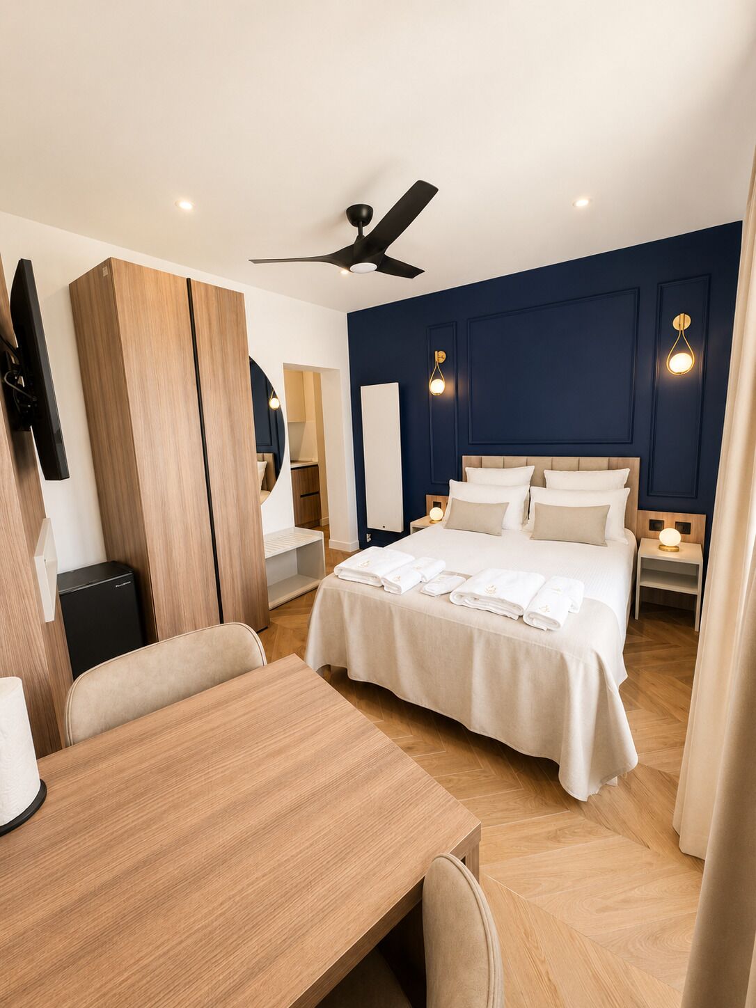 Ein Hotelzimmer mit einem Bett, Nachttischen, einem Schreibtisch, einem Sessel sowie einem Deckenventilator und einem Fernseher.
