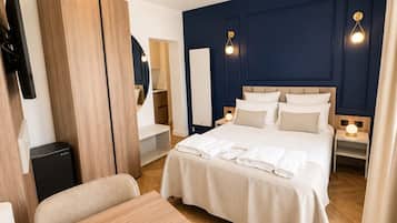 Ein Hotelzimmer mit einem Bett, Nachttischen, einem Schreibtisch, einem Sessel sowie einem Deckenventilator und einem Fernseher.