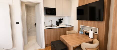 Una cocina compacta con microondas, lavamanos y un televisor de pantalla plana montado en la pared.