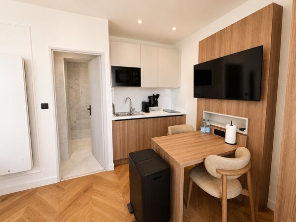 A compact kitchen with a microwave, sink, and a flat-screen TV mounted on the wall. - The Originals Residence, Les Sources Callou, Vichy (Vichy)