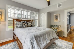 A bedroom with a large bed, a window with blinds, a door, and a small round table with a lamp. - < 1 Mi to Houston Museum District: Convenient Apt! (Houston)