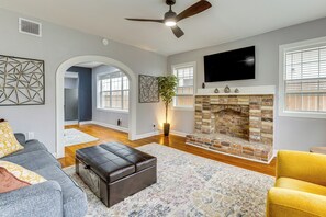 A living room with a fireplace, a ceiling fan, and a television mounted on the wall. - < 1 Mi to Houston Museum District: Convenient Apt! (Houston)