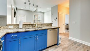 A modern kitchen with blue cabinets, a granite countertop, and a dishwasher. - Prime ATL Spot! Updated Condo Steps to Marta (Atlanta)