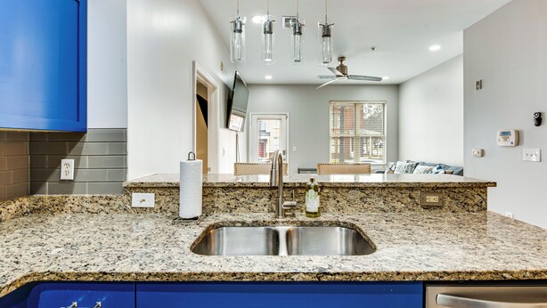 A kitchen with granite countertops, a stainless steel sink, blue cabinets, and pendant lights. - Prime ATL Spot! Updated Condo Steps to Marta (Atlanta)