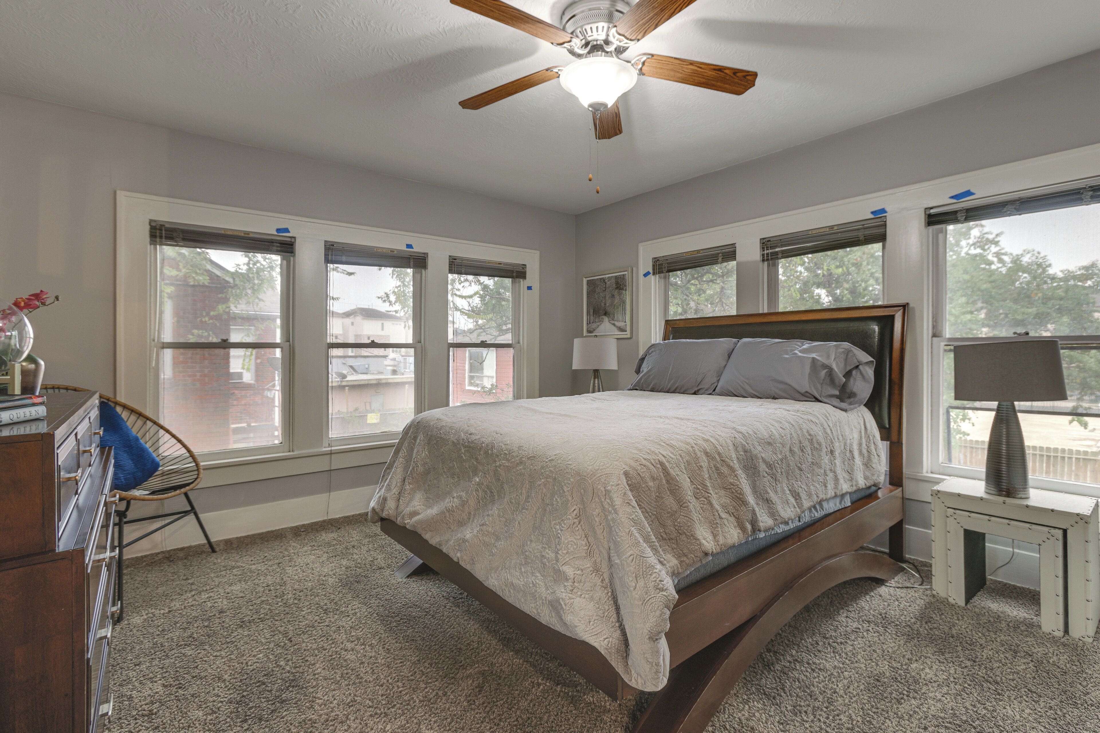 A bedroom with a bed, a ceiling fan, and large windows.
