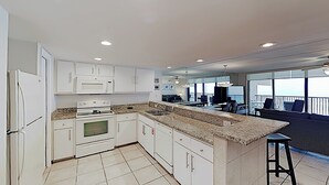 A modern kitchen with white cabinets, a granite countertop, and a built-in oven. - 10th-floor 3BR Beachfront Condo w/ Views & Pool (South Padre Island)