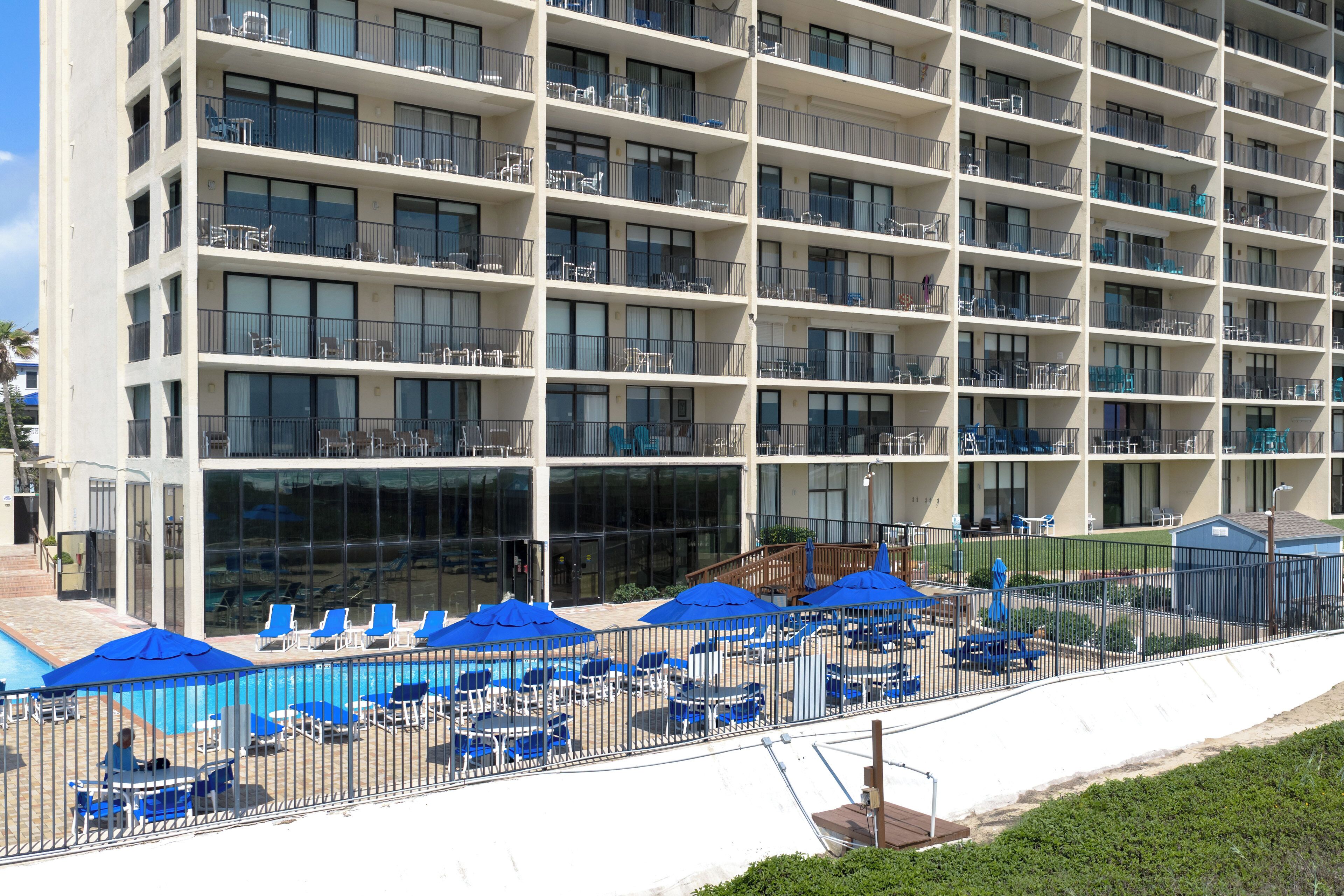 A multi-story hotel with balconies, a swimming pool, and outdoor seating areas.