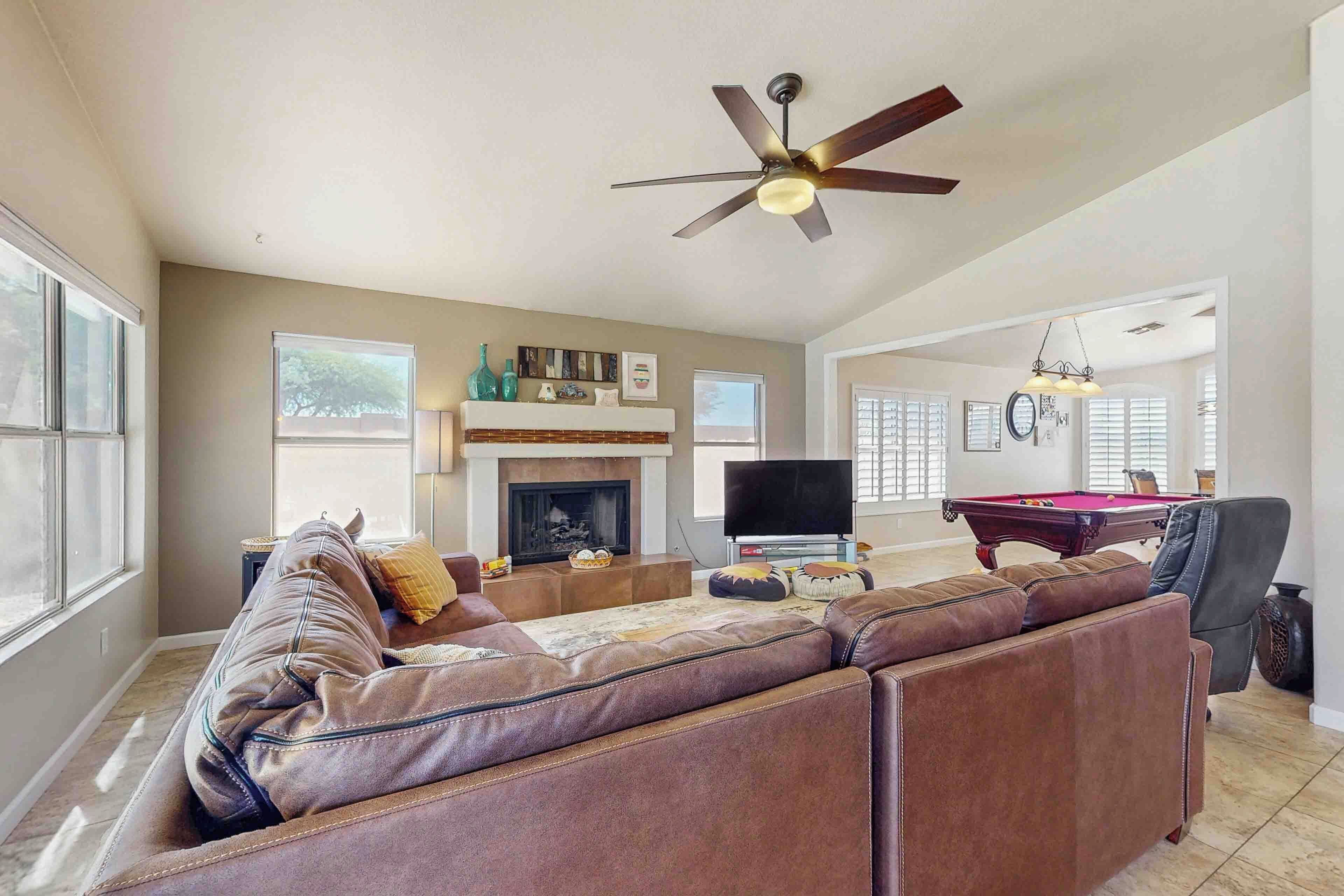 A spacious living room with a fireplace, a pool table, and a comfortable seating area.