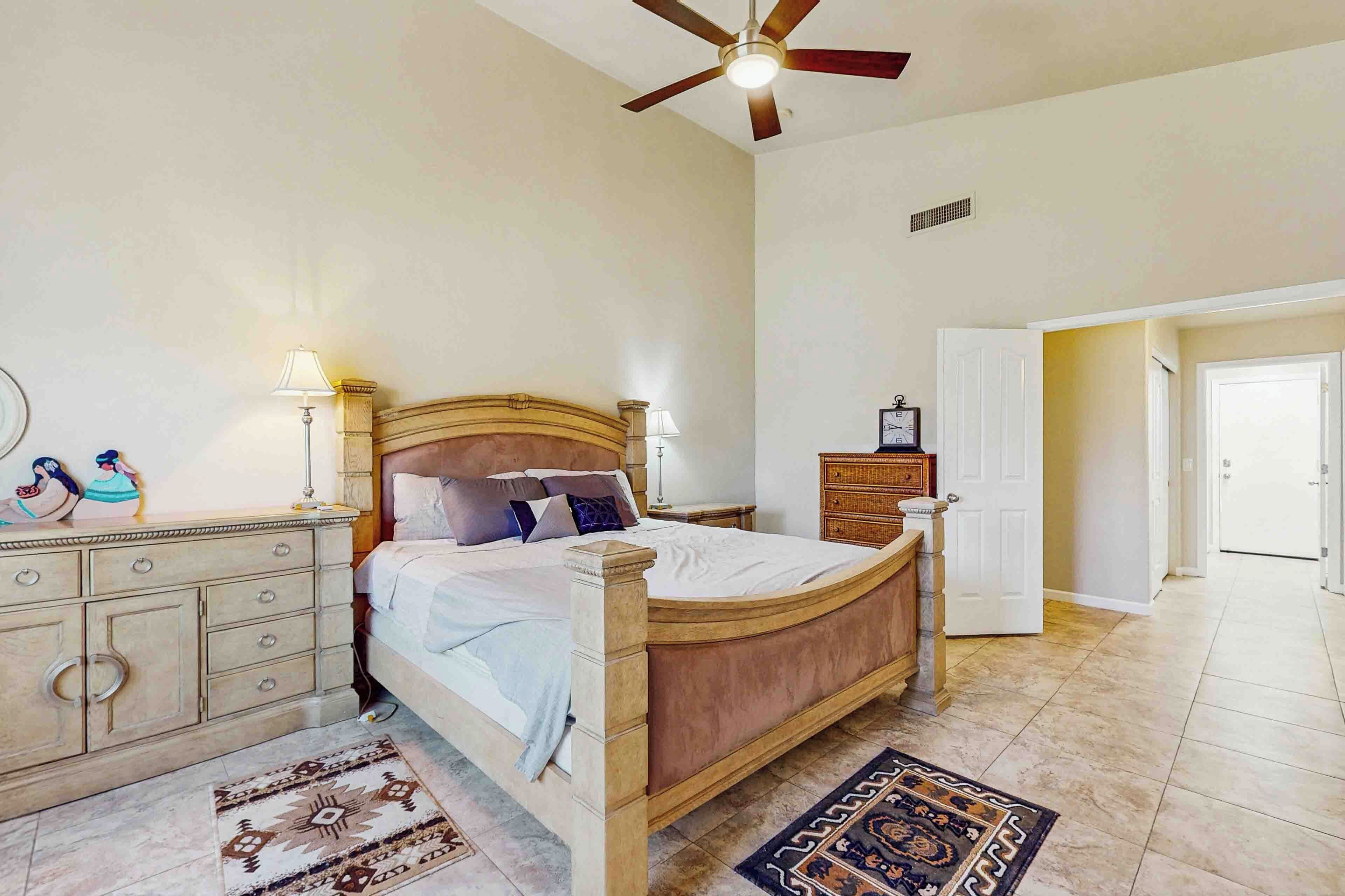 A bedroom with a wooden bed, bedside lamps, a dresser, and a patterned rug.