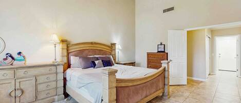 A bedroom with a wooden bed, bedside lamps, a dresser, and a patterned rug.