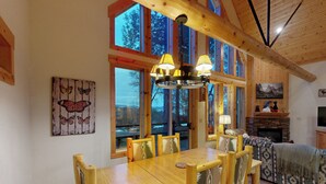 Un tavolo da pranzo in legno con sei sedie, un lampadario e ampie finestre che danno su un panorama esterno.