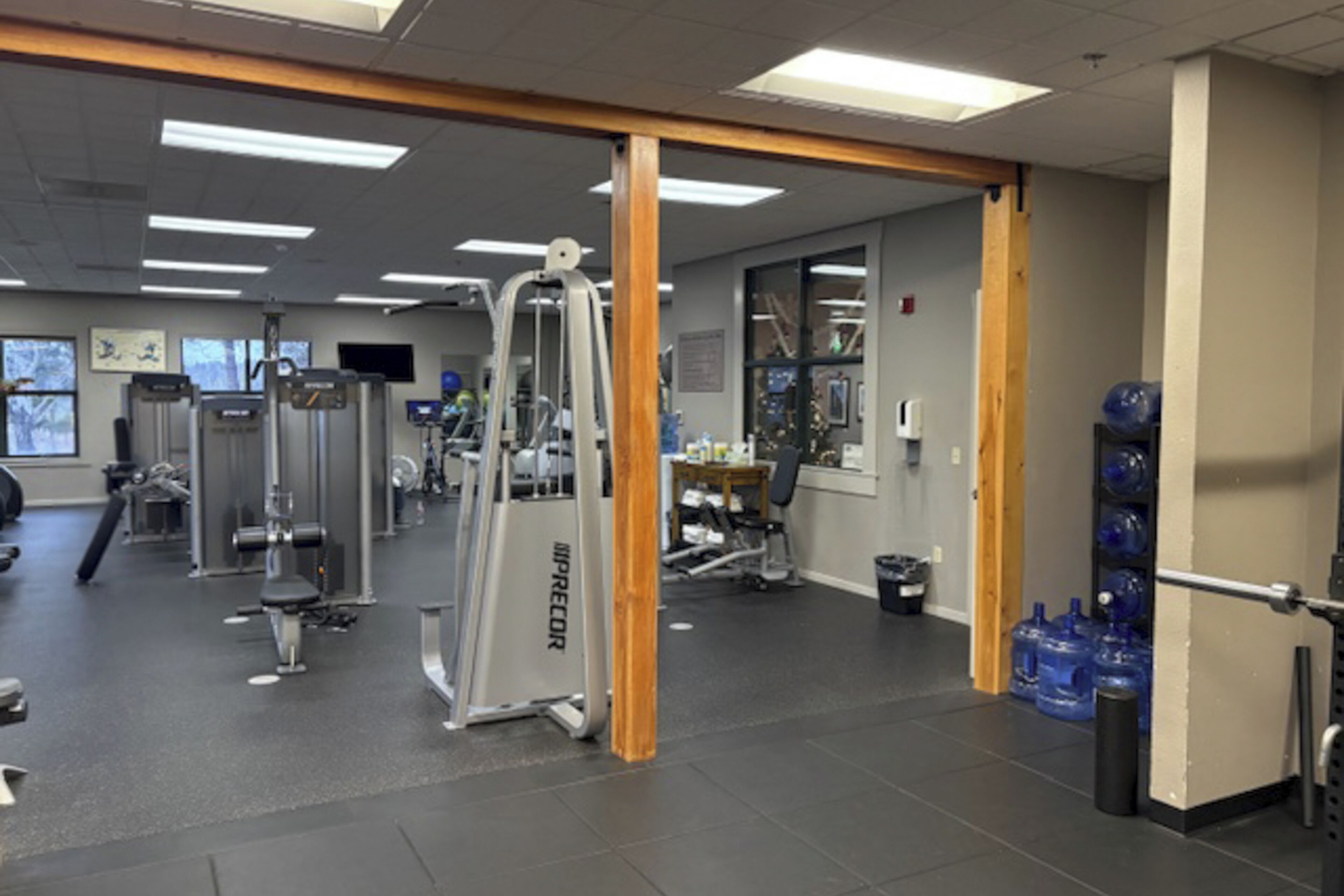 A gym with various exercise machines, a water dispenser, and exercise balls.