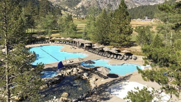 Ein Resort mit mehreren Swimmingpools, Liegebereichen und einer Bergkulisse.