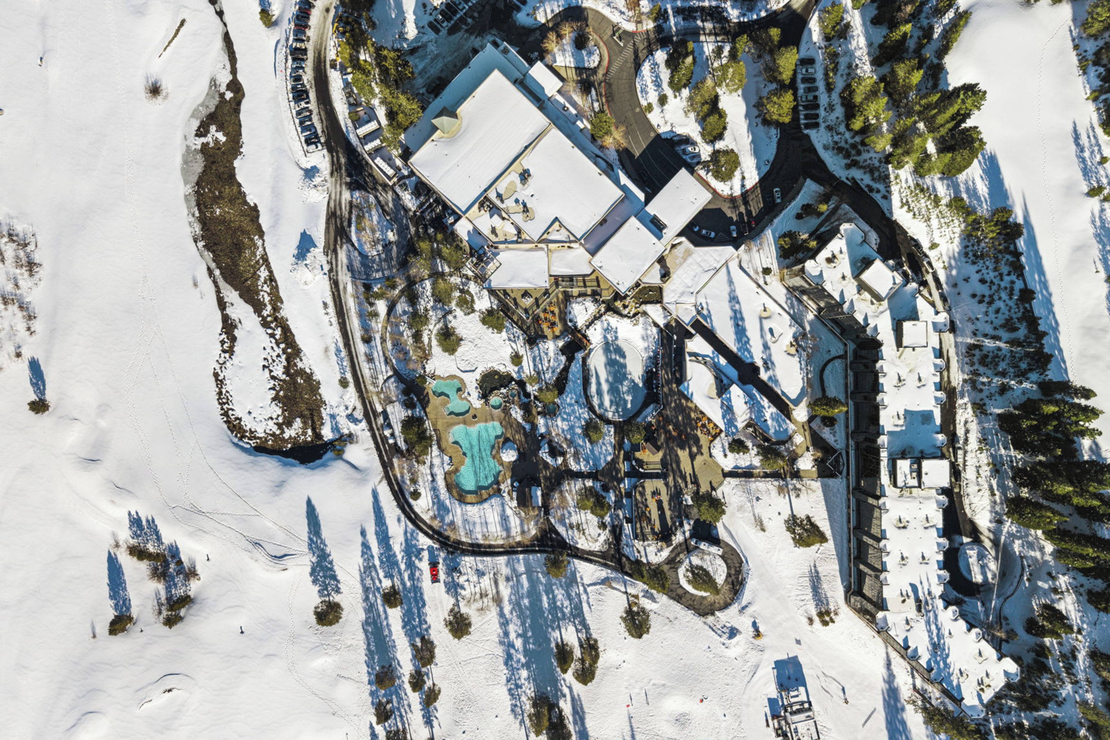 An aerial view of a snow-covered area with buildings, roads, and trees.