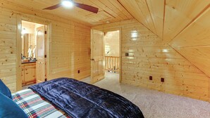 Ein Schlafzimmer mit einem Bett, einem Deckenventilator und Holzwänden.