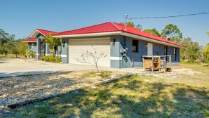 Ein zweistöckiges Haus mit rotem Dach, einer Garage und einer kleinen Terrasse.