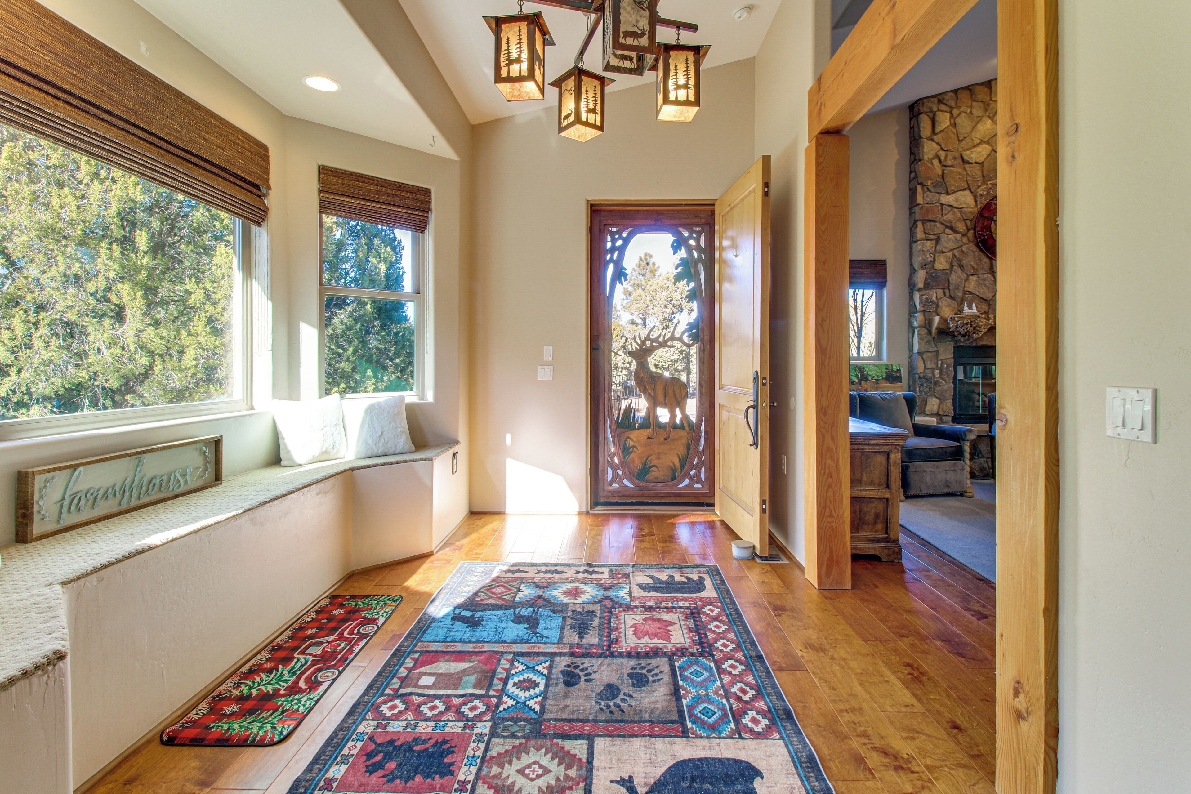 A hallway with a patterned rug, wooden bench, and a stone fireplace.
