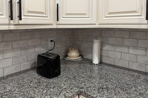 A kitchen with white cabinetry, a granite countertop, a toaster, a decorative bowl, and a paper towel holder. - 2 Mi to Lake Tomahawk Park! Quiet Escape w/ Deck (Black Mountain)